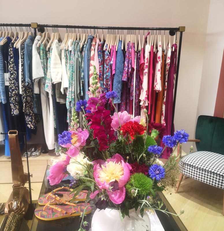 Bouquet fuchsia devant un portant de vêtements femme