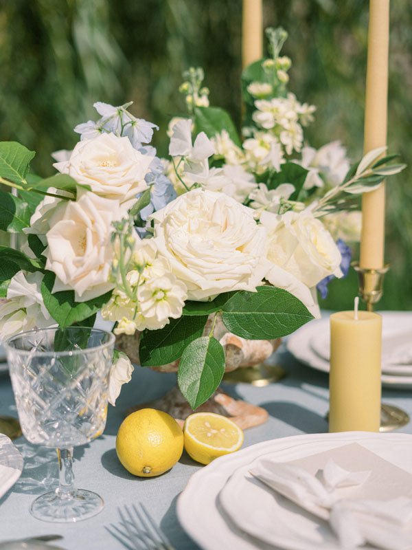 Bouquet centre de table mariage haut de gamme, esprit Dolce vita avec des citrons et une nappe bleue ciel.
